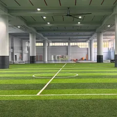 A wide view of our pristine indoor turf arena. This versatile space is used for everything from football and agility drills to group fitness sessions and community events.
