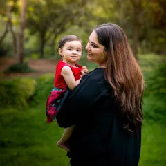 The simple act of a mother holding her child becomes a timeless memory. This outdoor portrait uses the natural greenery and soft light to create a warm and intimate feel.
