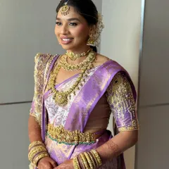 A beautiful portrait of the smiling bride. Her makeup is kept fresh and radiant to complement the lavender and gold tones of her traditional wedding saree.