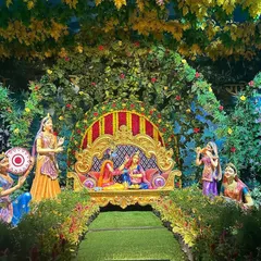 We recreated a scene from Vrindavan with this elaborate Janmashtami jhanki. The setup features lush greenery, a beautifully decorated throne for Radha and Krishna, and statues of gopis, making the story come to life.