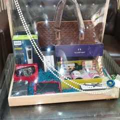 A luxury hamper for a groom, featuring a Philips grooming kit, a stylish laptop bag, The Body Shop products, and other accessories in a wooden tray.