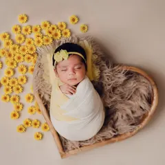 A heart full of sunshine. This newborn baby girl is nestled in a heart-shaped basket, surrounded by bright yellow flowers. I use creative props to add a touch of warmth and personality to my newborn photoshoots.