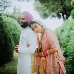 A serene portrait of a Sikh bride resting her head on the groom's shoulder in a beautiful garden setting.