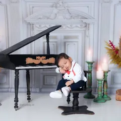 A wider shot of the little pianist asleep at his stool. The full view shows the grand piano and the elegant, candle-lit room setting.