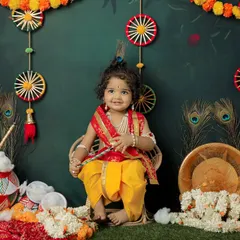 A charming portrait of a toddler dressed as Lord Krishna, sitting happily in a festive setting. We pay close attention to every detail, from the costume to the props.
