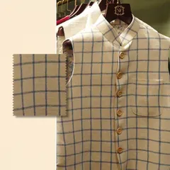 Feel the richness of texture that redefines luxury. A close-up of a checked linen Nehru vest, with a swatch to emphasize the quality of the weave.