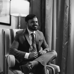 A candid black and white portrait of a groom, smiling during a quiet moment.