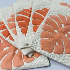 A set of stylish cushion covers featuring a modern appliqué of a Monstera leaf. The gradient of orange tones and the pebble quilting make these a chic home accessory.
