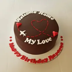 A sweet and simple "Welcome Home" cake. The chocolate cake is decorated with a plane's flight path creating a heart, perfect for celebrating the return of a loved one.