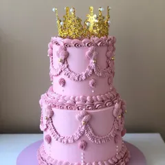 I love bringing vintage charm to life with buttercream. This two-tiered pink Lambeth cake, with its intricate piping and a regal gold crown, was perfect for a princess-themed birthday.
