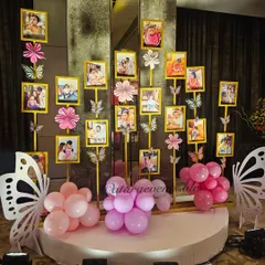 A beautiful and personal touch, this photo gallery displays pictures from the baby's first year on stands decorated with paper flowers and butterflies.