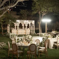 The full evening setup for the 'Sheesh Mahal' reception, with mirrored tables reflecting the candlelit structures and surrounding trees.