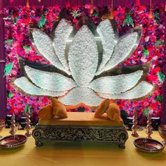 A vibrant and colorful backdrop for a Haldi or Mehendi ceremony, featuring a large lotus made of white crystals against a wall of bright pink flowers.