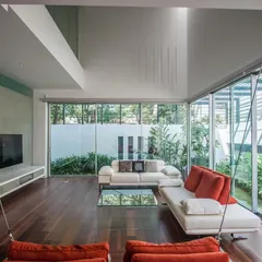 The family room in the Sandeep & Neelam Agarwal residence is wrapped in floor-to-ceiling glass, erasing the boundary with the lush garden outside. An indoor swing adds a playful element to this light-filled, open-concept living space.