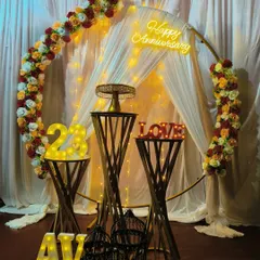 I combine classic and modern elements for a unique look. This anniversary setup features a circular frame decorated with a floral garland, a custom neon sign, and light-up marquee numbers for the anniversary year, all tied together with elegant draping.
