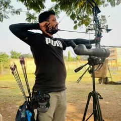 I take a moment for my own practice, using a spotting scope to analyze my shots with a compound bow.