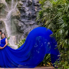 We used a stunning waterfall as the backdrop for this maternity photo. The flowing blue gown mimics the movement of the water, creating a dynamic and natural feel for this expecting couple's portrait.