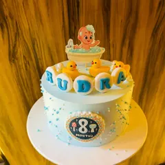 An adorable cake for an 8-month milestone, featuring a Cocomelon-inspired baby in a bathtub with little yellow duckies.