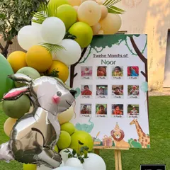 We love adding personal touches, like this "Twelve Months of Noor" photo board. It's a beautiful way for guests to see the baby's journey, framed by a cute bunny balloon and a safari-themed balloon arrangement.