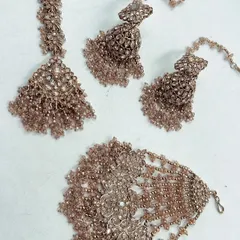 This elegant Haldi jewellery set is designed with champagne-colored beads for a subtle, classy look. The rental set includes a maang tikka, hathphool, and matching earrings.