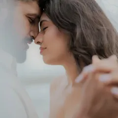 An intimate close-up where a couple holds each other, lost in the moment. This candid shot, with a soft foreground element, creates a feeling of peeking into a private, heartfelt connection.