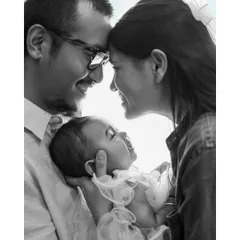 This black and white family portrait captures the pure happiness and connection between parents and their smiling baby, creating a timeless and emotional memory.