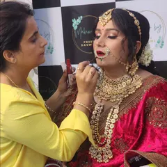 The final touches. Here I am applying lipstick to complete the bride's regal look, ensuring every detail is perfect.