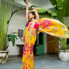 Capturing movement and color is my passion. In this outdoor shot, the model's dynamic pose makes the vibrant yellow floral saree come alive, showing the beautiful drape and flow of the fabric against a lush green background for a fresh, energetic lookbook image.