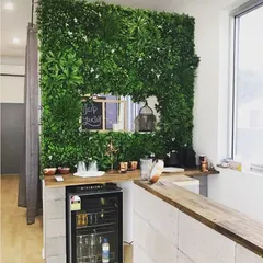 We brought the outdoors into this service area with a stunning vertical garden wall. This artificial green wall provides a lush, maintenance-free backdrop for the wooden countertop and bar area.