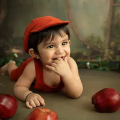A curious moment from the apple-themed shoot, as the baby explores the props. These sessions are designed to be playful and engaging for your child.