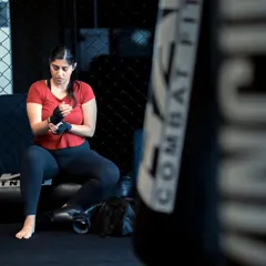 A female fighter wraps her hands before training, a ritual that prepares both the hands and the mind for the work ahead.