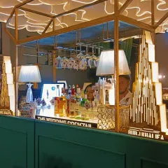 This Art Deco inspired bar features geometric patterns, elegant lamps, and a mirrored backsplash, perfect for a glamorous 1920s themed wedding or a sophisticated cocktail night.