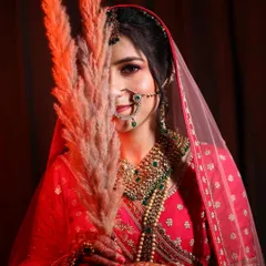 A creative bridal portrait using a prop to partially obscure the face. The warm red lighting and her subtle smile create an image that is both mysterious and beautiful.