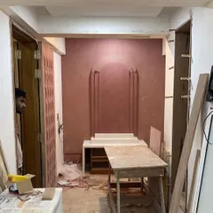 A work-in-progress shot of the mandir space at Vishu Home. This shows the raw construction and application of the textured wall finish before the final elements are installed.