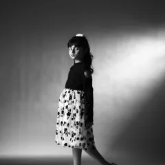 A walking pose that shows confidence and movement. This black and white shot is great for a portfolio as it demonstrates her comfort in front of the camera and her natural sense of style.