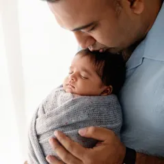 A father's gentle kiss on his sleeping baby's head. This is a simple, powerful expression of love and protection.