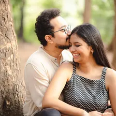 A warm, color portrait of Soham giving Anjum a gentle kiss on the forehead. The natural setting and their relaxed expressions make this a sweet and timeless image.