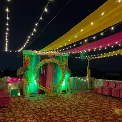 A wide view of the terrace decorated for a Haldi and Mehndi ceremony, with colorful fabric draping from the ceiling.