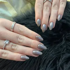 A sophisticated and subtle chrome manicure. These almond-shaped nails are coated in a gunmetal grey chrome powder that shifts in the light, creating a mesmerizing, liquid-metal effect.