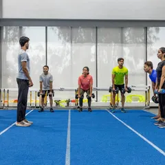 Our coach oversees a group performing deadlifts, ensuring correct technique and posture. This exercise is crucial for developing the posterior chain muscles essential for running.