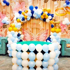 A close-up of the ring ceremony table, which is creatively constructed from white and blue balloons. The butterfly wings add a touch of whimsy.