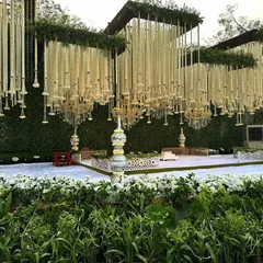 This is what I call a dream wedding setup. The stage features a massive green wall with hanging floral chandeliers made of tuberoses, creating a truly magical and grand look for an outdoor reception.
