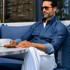 Casual elegance perfected. Our custom indigo denim shirt, paired with crisp white pleated trousers, redefines the weekend brunch or business-casual look. It’s a testament to how bespoke tailoring elevates even the most relaxed attire.