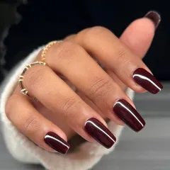A close-up of the flawless, glossy burgundy manicure. The color is rich and the finish is like glass, showcasing a perfect gel application.