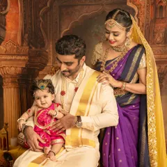 A complete family portrait for Janmashtami. The parents look on lovingly as their little one, dressed as Krishna, sits happily in dad's lap.