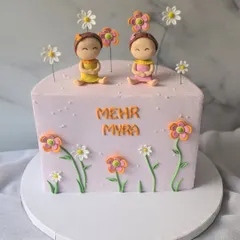 A sweet half-birthday cake for twin girls, Mehr and Myra. This square cake is decorated with two cute figurines sitting in a field of flowers.