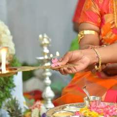 A hand offering a flower to the sacred flame (diya) during an auspicious ceremony. I use lighting to emphasize the warmth and spirituality of these moments.