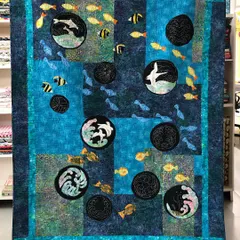 This award-winning sea quilt was featured at the Dubai Quilt Festival. It uses appliqué and traditional Japanese Sashiko stitching to create a dynamic underwater scene with fish and dolphins.