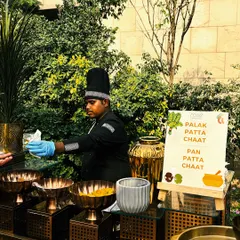 We bring classic Indian street food to life with our live chaat counters. Here, a chef prepares Palak Patta Chaat and Pan Patta Chaat at an elegant outdoor setup, complete with stylish serveware and fresh ingredients.