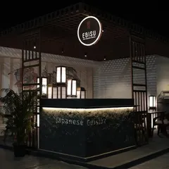A wide shot of the 'Ebisu' Japanese fine-dining pop-up we created for the India Art Fair. The design features a structured, dark wood frame, a glowing circular brand sign, and traditional Japanese lanterns to create an authentic and inviting atmosphere at night.